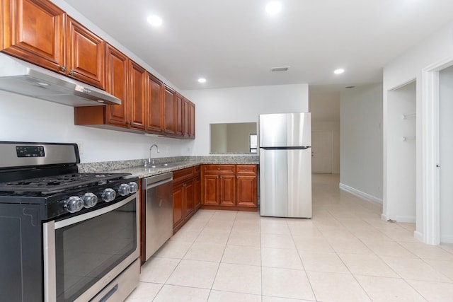 kitchen with light stone counters, sink, light tile patterned floors, and stainless steel appliances