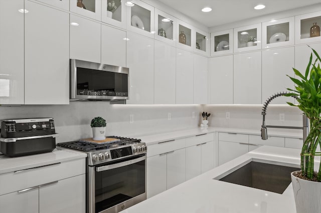 kitchen with white cabinetry, stainless steel appliances, sink, and backsplash