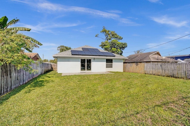 back of house with a yard and solar panels