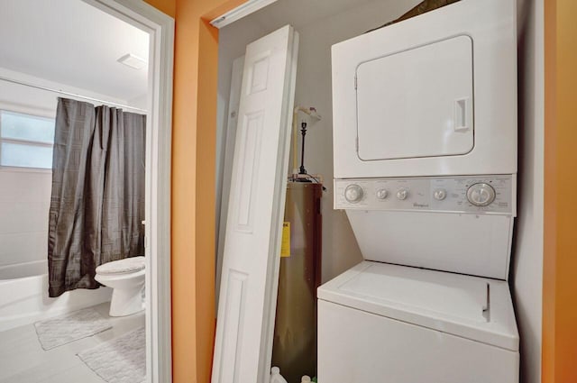 laundry area with stacked washer and dryer, light tile patterned floors, and water heater