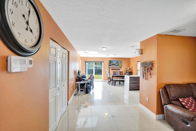 hallway featuring a textured ceiling and light tile patterned flooring