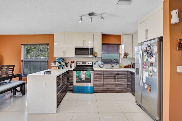 kitchen with light tile patterned flooring, appliances with stainless steel finishes, sink, and white cabinets