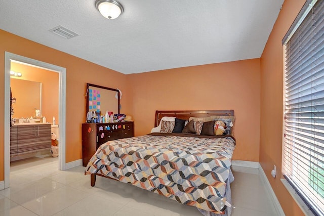 tiled bedroom with a textured ceiling and ensuite bathroom