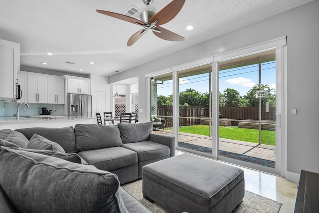 living room with sink, a textured ceiling, and ceiling fan