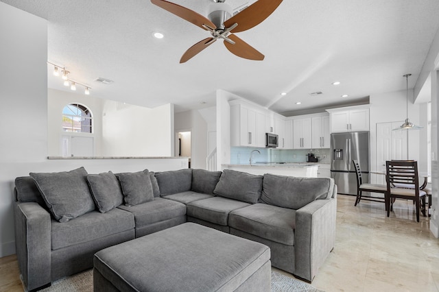 living room with ceiling fan, sink, and a textured ceiling