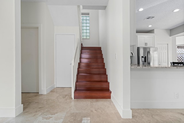 stairs featuring a textured ceiling