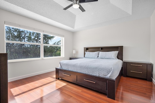 bedroom featuring hardwood / wood-style flooring, a raised ceiling, and a textured ceiling