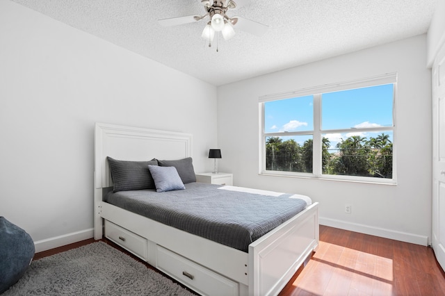 bedroom with ceiling fan, hardwood / wood-style flooring, and a textured ceiling