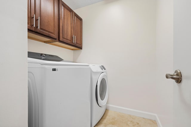 clothes washing area featuring cabinets and washer and clothes dryer