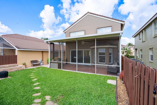 back of property featuring ceiling fan, a patio area, a sunroom, and a lawn