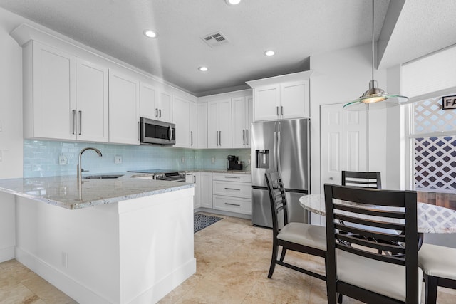 kitchen with white cabinetry, stainless steel appliances, kitchen peninsula, and sink