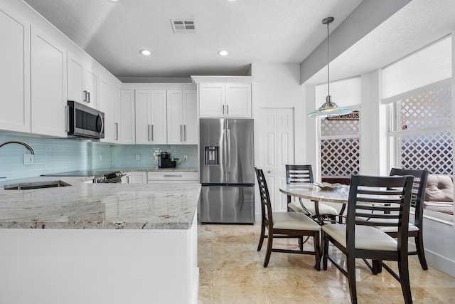 kitchen with pendant lighting, sink, appliances with stainless steel finishes, light stone countertops, and white cabinets