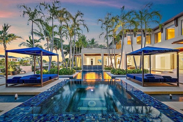 177 Commodore Dr, Jupiter, FL 33477 - pool at dusk featuring an outdoor hot tub, an outdoor pool, and a patio area
