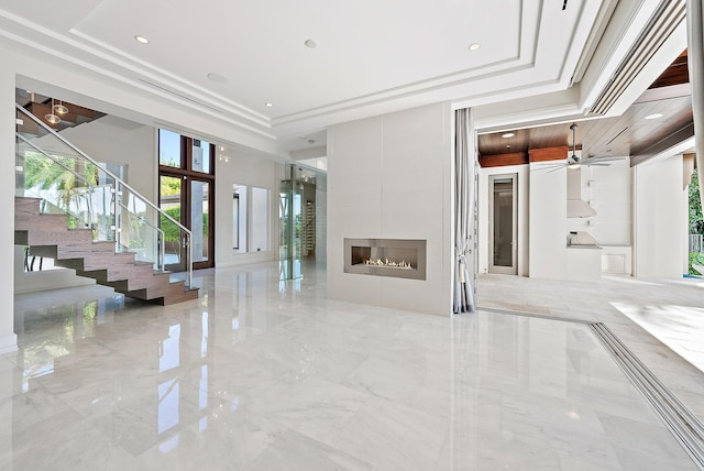 177 Commodore Dr, Jupiter, FL 33477 - unfurnished living room with a tray ceiling, stairway, marble tiled flooring, ceiling fan, and a fireplace