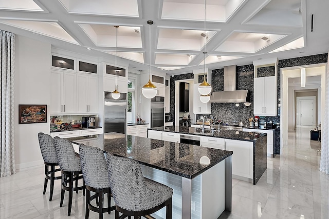 kitchen with a spacious island, marble finish floor, wall chimney range hood, and stainless steel built in refrigerator