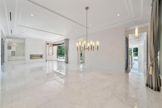 177 Commodore Dr, Jupiter, FL 33477 - empty room featuring a raised ceiling, a chandelier, light marble finish flooring, a glass covered fireplace, and recessed lighting