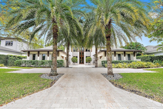 view of front of property featuring decorative driveway, a front lawn, and stucco siding