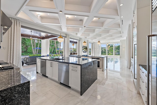 177 Commodore Dr, Jupiter, FL 33477 - kitchen with a kitchen island with sink, coffered ceiling, dark stone counters, pendant lighting, and a sink