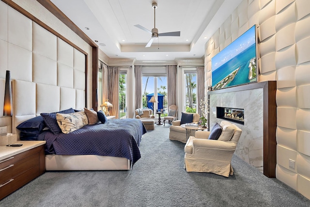 carpeted bedroom featuring a high end fireplace, recessed lighting, a raised ceiling, and access to exterior