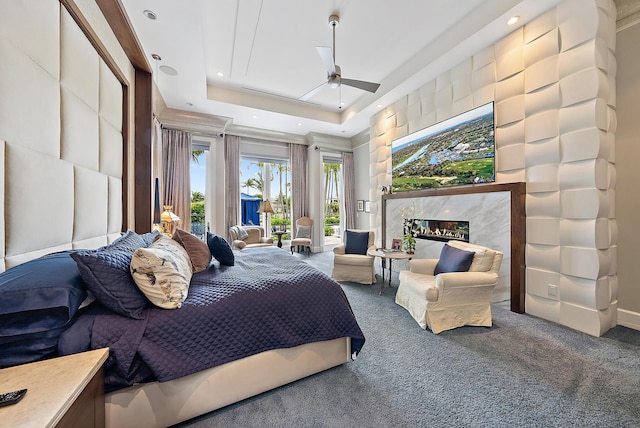 bedroom with a fireplace, recessed lighting, a raised ceiling, access to outside, and carpet flooring