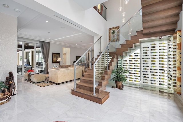 entryway featuring a towering ceiling, stairway, ornamental molding, marble finish floor, and recessed lighting