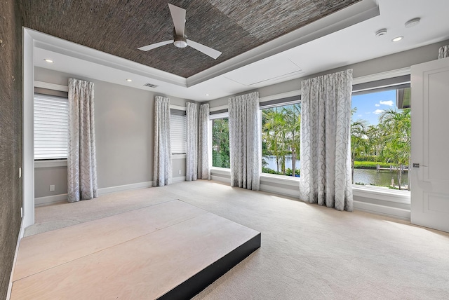 177 Commodore Dr, Jupiter, FL 33477 - carpeted bedroom with a tray ceiling, a water view, baseboards, recessed lighting, and a ceiling fan