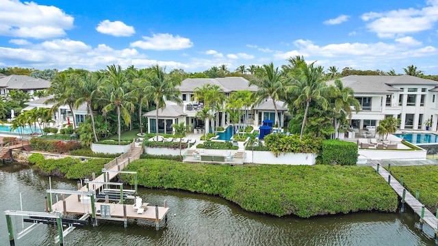 rear view of property with a patio area, boat lift, a lawn, and a water view