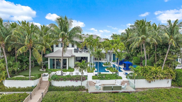 rear view of house with a lawn, an outdoor pool, a balcony, stairs, and a patio area