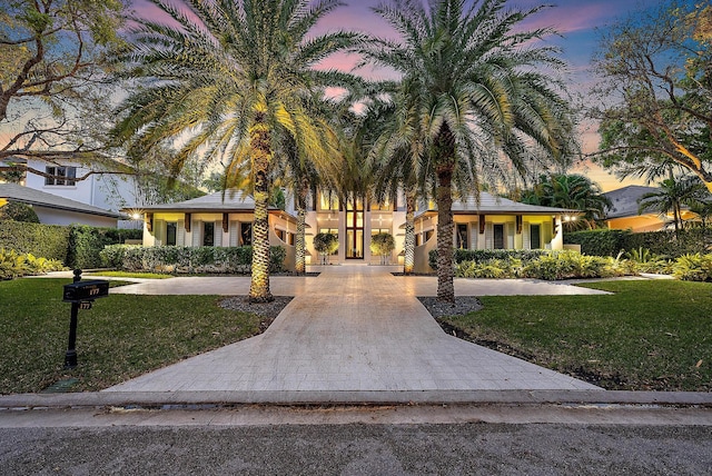 surrounding community featuring decorative driveway and a yard