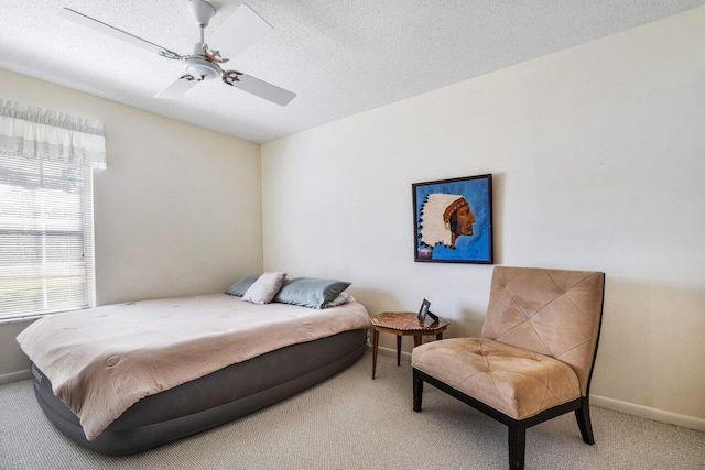 carpeted bedroom featuring ceiling fan and a textured ceiling