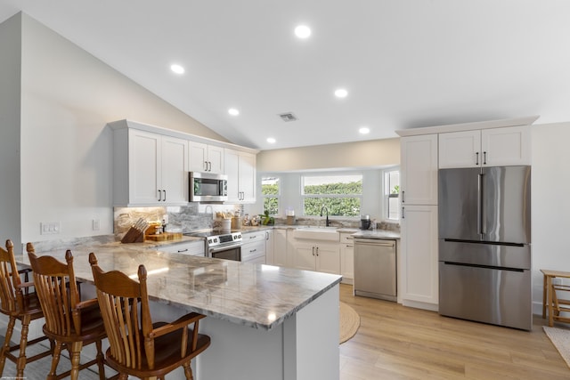 kitchen featuring appliances with stainless steel finishes, a breakfast bar area, white cabinets, and kitchen peninsula