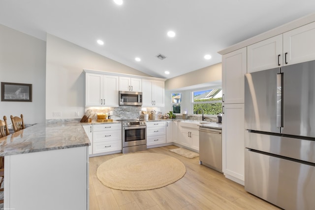 kitchen featuring appliances with stainless steel finishes, a breakfast bar, sink, white cabinets, and kitchen peninsula
