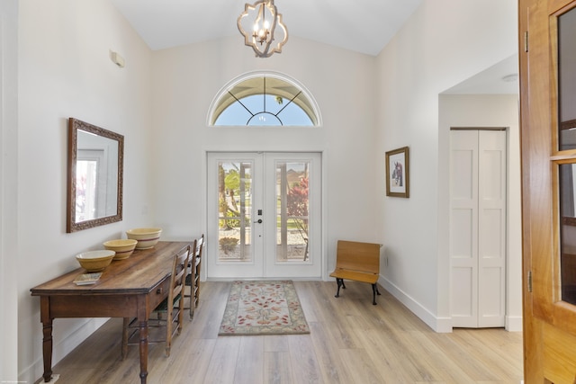 entrance foyer featuring french doors, lofted ceiling, light hardwood / wood-style floors, and a notable chandelier