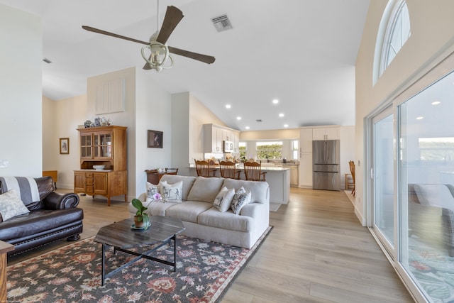 living room featuring high vaulted ceiling, ceiling fan, and light wood-type flooring