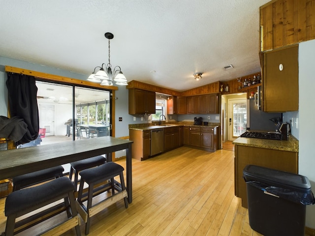 kitchen with lofted ceiling, sink, light wood-type flooring, stainless steel dishwasher, and pendant lighting