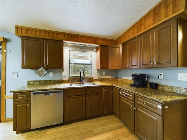 kitchen featuring sink, dark stone counters, stainless steel dishwasher, a textured ceiling, and light hardwood / wood-style flooring
