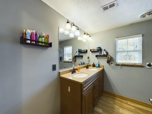 bathroom with hardwood / wood-style flooring, vanity, and a textured ceiling