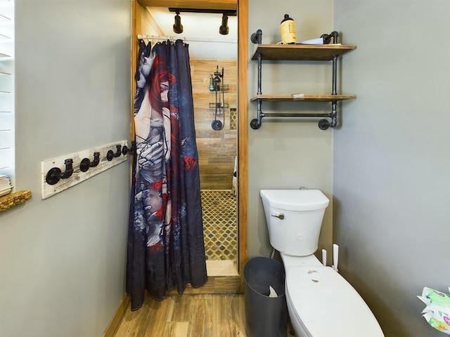 bathroom with wood-type flooring, toilet, and curtained shower