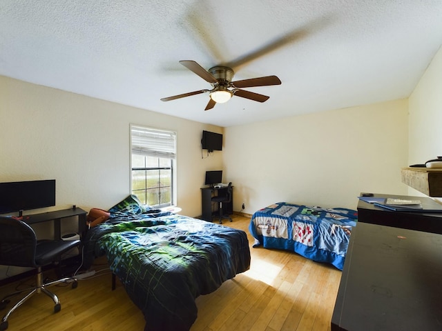bedroom featuring ceiling fan, a textured ceiling, and light wood-type flooring