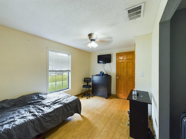 bedroom with ceiling fan, a textured ceiling, and light hardwood / wood-style flooring