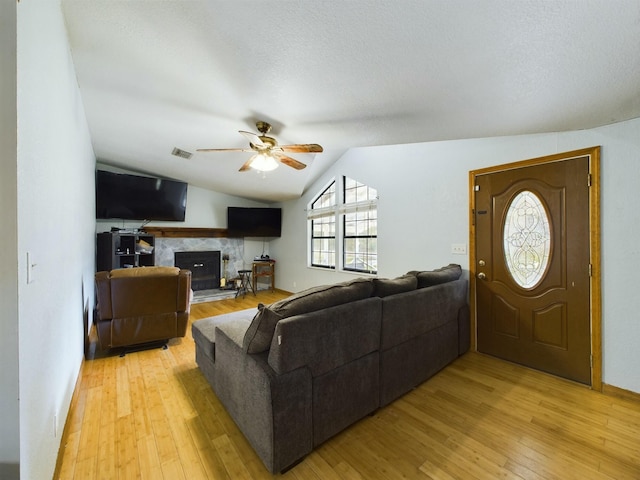 living room featuring lofted ceiling, a textured ceiling, ceiling fan, and light hardwood / wood-style flooring