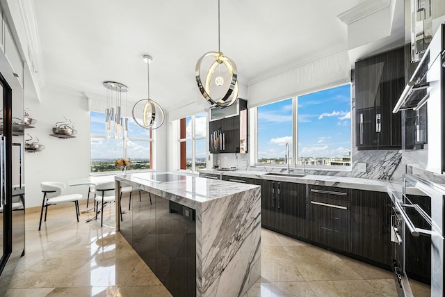 kitchen featuring sink, a center island, ornamental molding, pendant lighting, and decorative backsplash