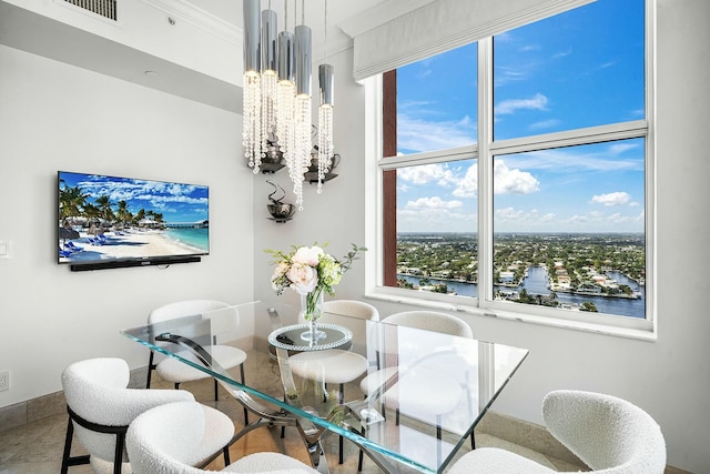 dining room with a water view, ornamental molding, and a notable chandelier