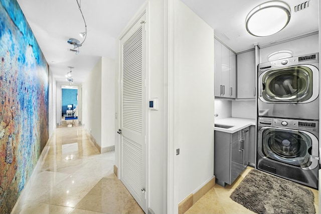 washroom with cabinets, stacked washer and dryer, and light tile patterned floors