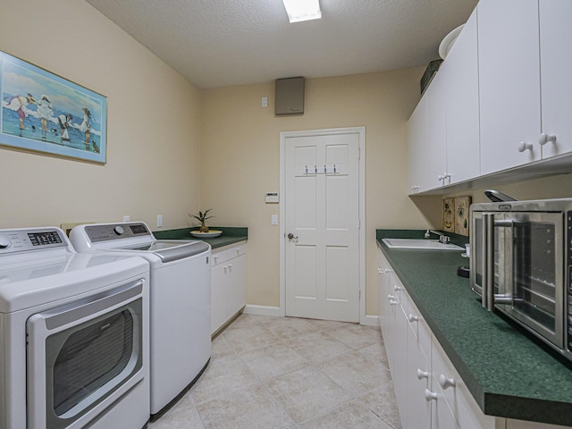 clothes washing area featuring cabinets, sink, washer and dryer, and a textured ceiling