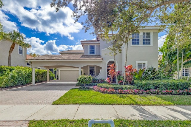 mediterranean / spanish house featuring a garage, a front yard, and a carport