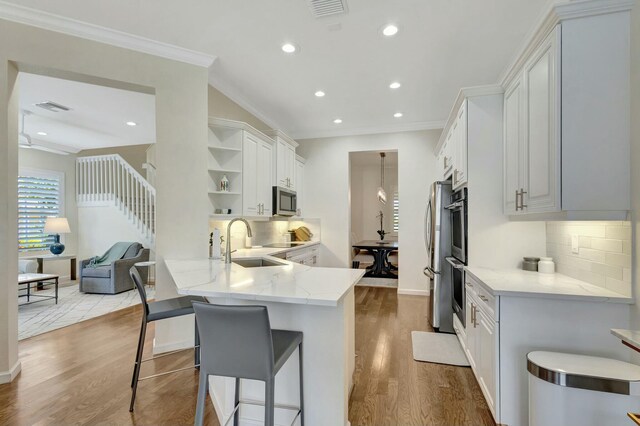 106 Via Santa Cruz, Jupiter, FL 33458 - kitchen featuring a sink, open shelves, wood finished floors, appliances with stainless steel finishes, and tasteful backsplash