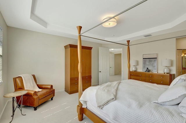 bedroom with light carpet and a tray ceiling