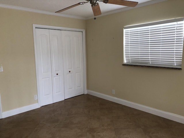 unfurnished bedroom with ceiling fan, ornamental molding, dark tile patterned flooring, and a closet