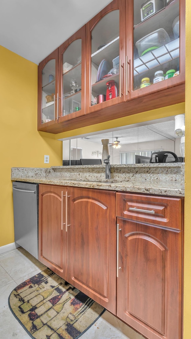 bar with light tile patterned flooring, light stone countertops, and stainless steel dishwasher